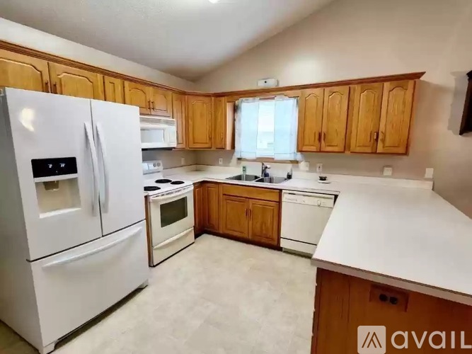 A kitchen with white appliances and wooden cabinets.