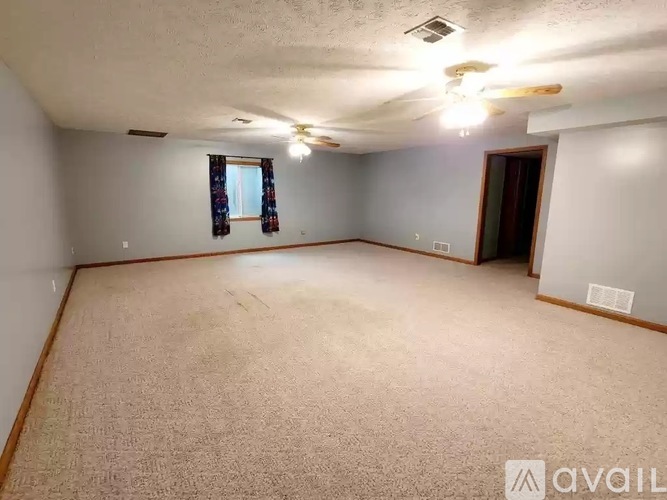 A room with a carpeted floor and a ceiling fan.