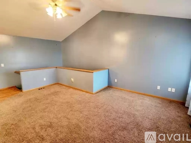 A room with a carpeted floor and a ceiling fan.