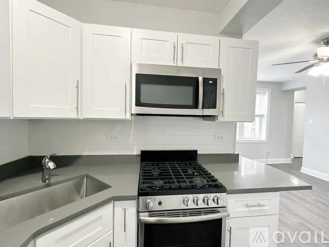 A kitchen with white cabinets and a black microwave above the stove.