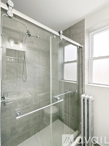 A modern bathroom with a glass shower stall and a window.