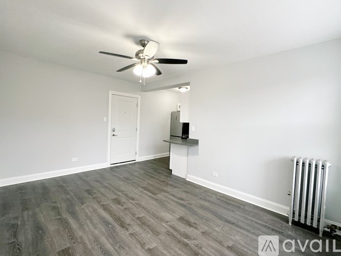 A spacious room with a ceiling fan and a radiator on the wall.