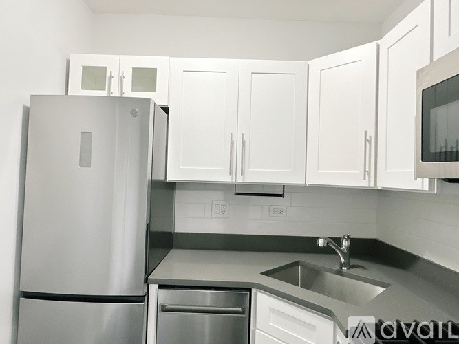 A kitchen with a stainless steel refrigerator, microwave, and sink.