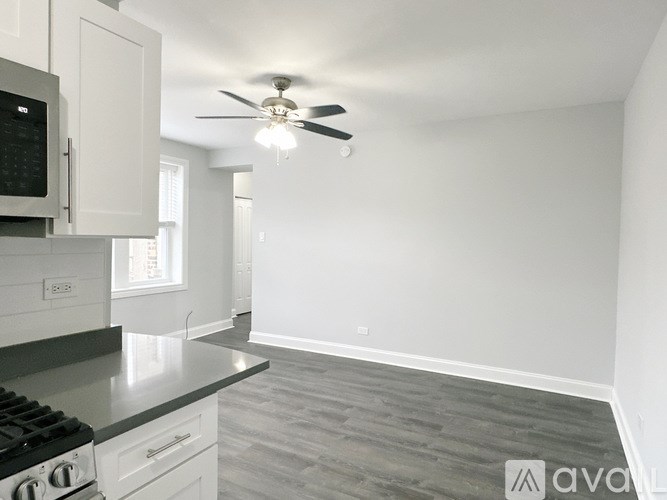 A kitchen with a stove, cabinets, and a ceiling fan.