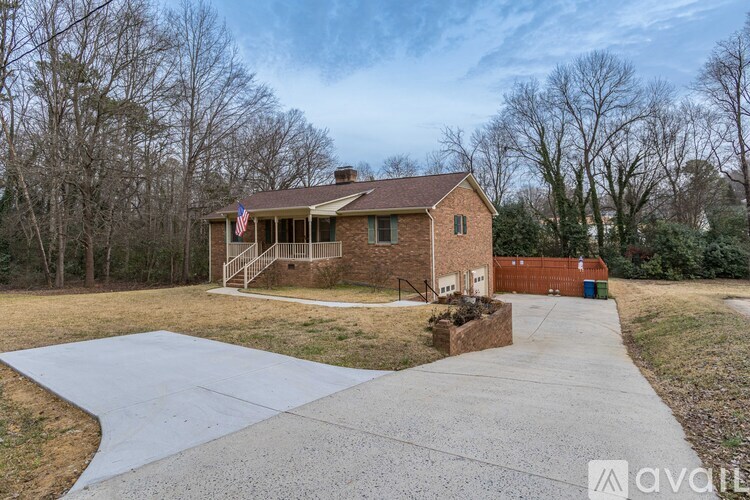 A house with a flag on the front porch is surrounded by trees.