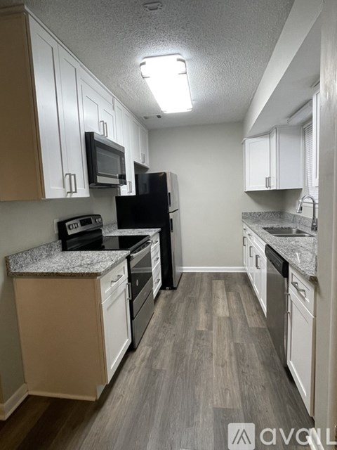 A kitchen with a black refrigerator, black oven, and black microwave.