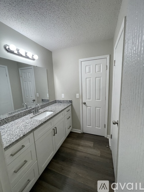 A bathroom with a sink, mirror, and cabinets.