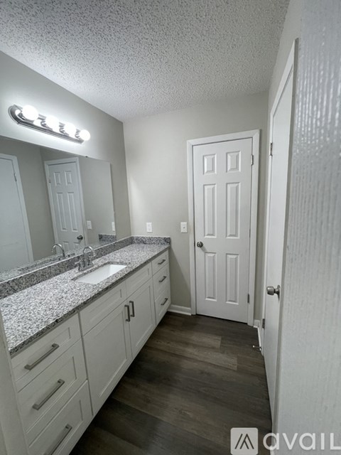 A bathroom with a sink, mirror, and cabinets.