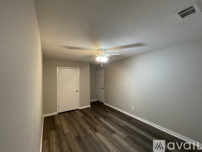A room with a ceiling fan and wooden flooring.