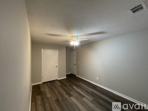A room with a ceiling fan and wooden flooring.
