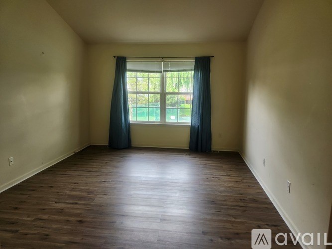 A room with wooden floors and a window with curtains.