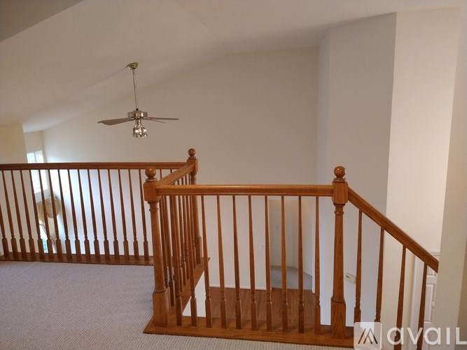 A wooden staircase with a fan above it.