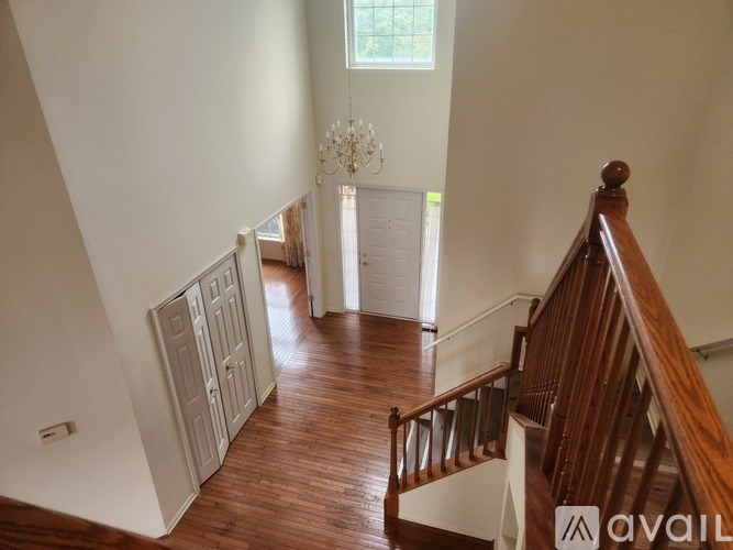 A wooden staircase with a chandelier in the background.