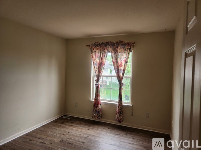 A room with a window and a wooden floor.