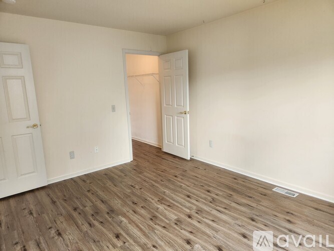 A room with wooden flooring and two white doors.