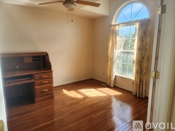 A room with a ceiling fan and a wooden floor.