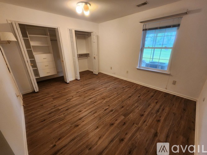 A room with wooden flooring and a window with a view of a building outside.