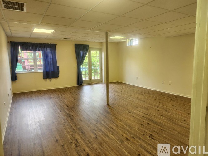 A room with wooden flooring and a window with blue curtains.