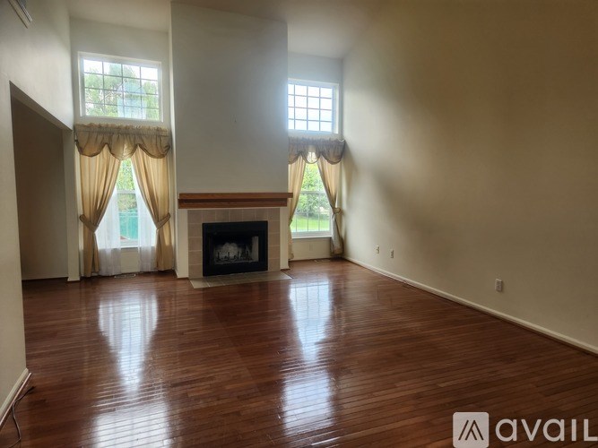 A room with a fireplace and two windows.