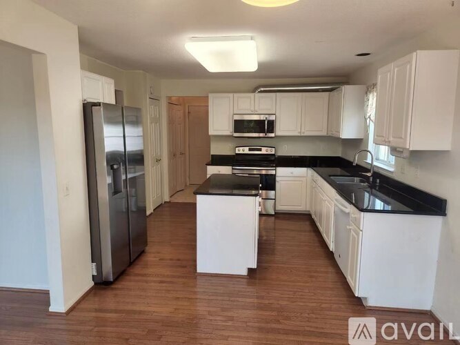 A kitchen with white cabinets and black countertops.