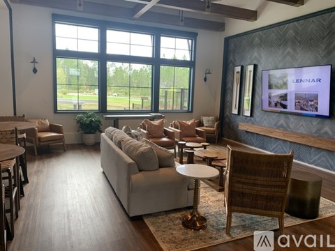 A living room with a couch, chairs, and a television displaying the word "LENNAR.".