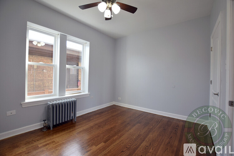 A room with a ceiling fan and a window with a view of a brick building outside.