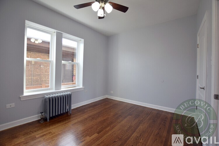 A room with a ceiling fan and a window with a view of a brick building outside.