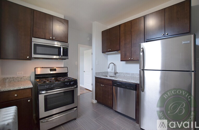 A kitchen with a stainless steel refrigerator and a microwave above the stove.
