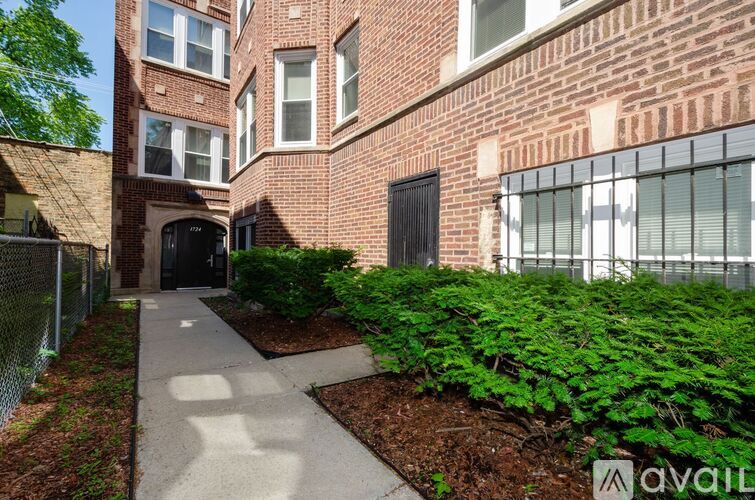 A brick building with a fence and bushes in front.
