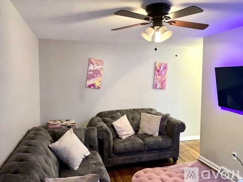 A living room with a grey couch and a ceiling fan.