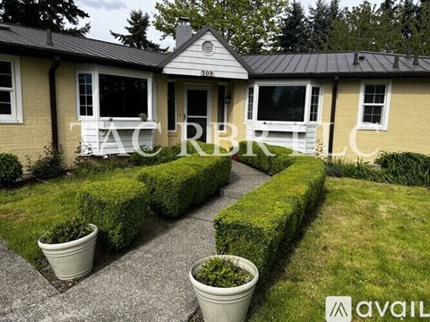A house with a well-maintained lawn and two potted plants in front.