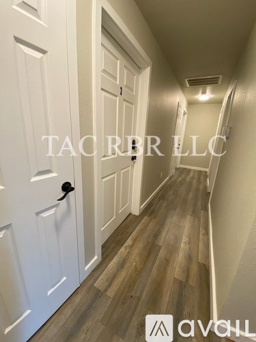 A hallway with a white door and wooden floors.