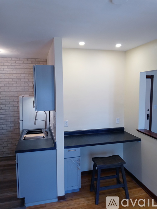A kitchen with a blue island and stool.