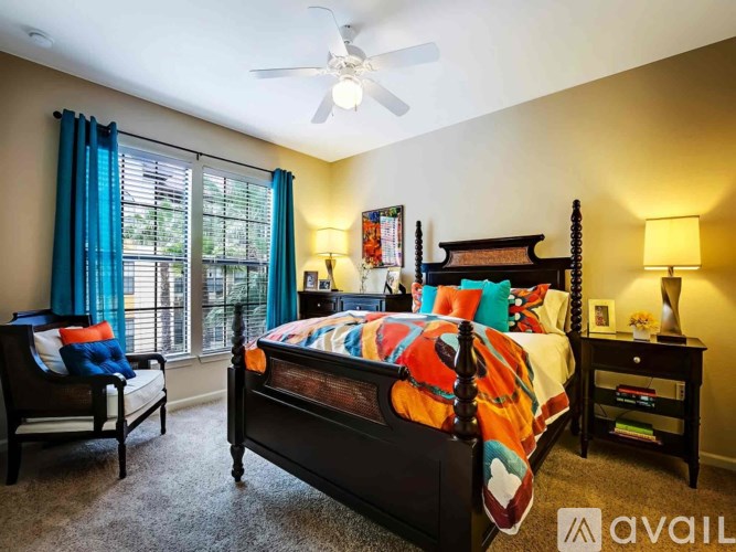 A bedroom with a bed, a chair, and a ceiling fan.
