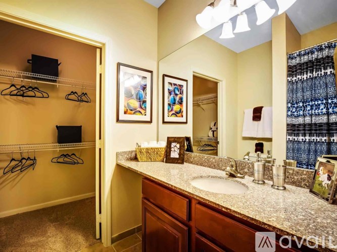 A bathroom with a sink, mirror, and a closet with clothes hanging.