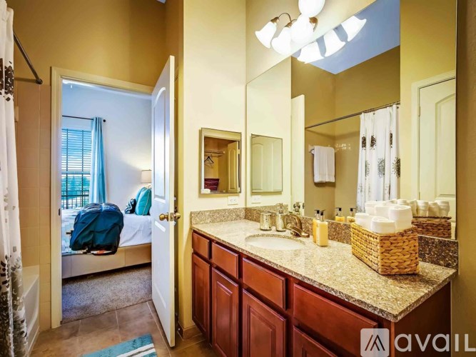 A bathroom with a bed in the corner and a mirror above the sink.