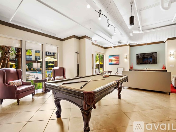 A room with a pool table and chairs.
