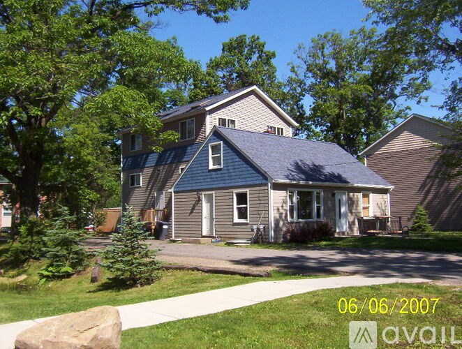 A house with a blue roof and a white door is surrounded by greenery.