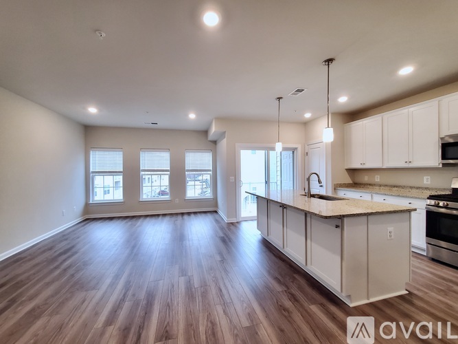 A spacious kitchen with wooden floors and white cabinets is available.