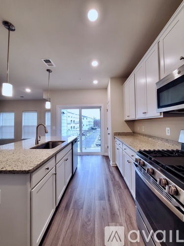 A modern kitchen with wooden floors and white cabinets.