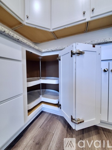 A kitchen with white cabinets and a wooden floor.