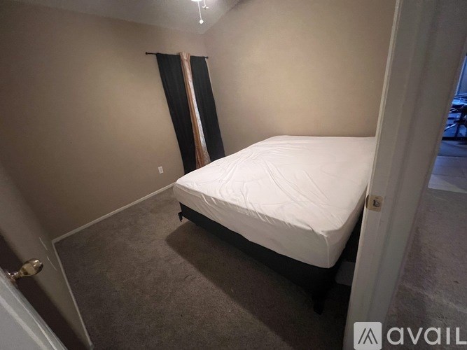 A bedroom with a white bed and carpeted floor.