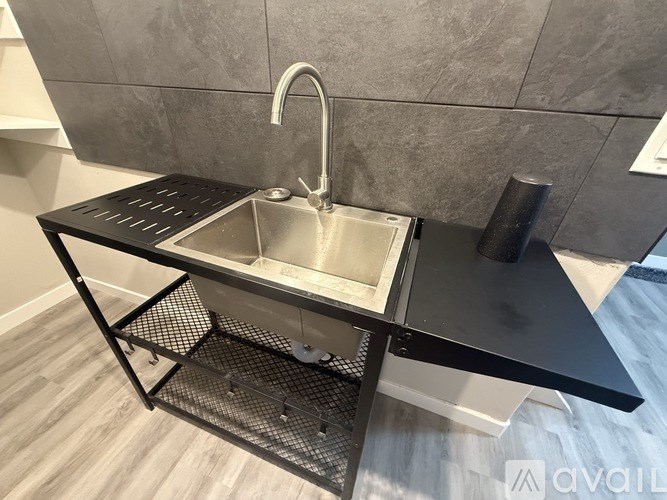 A black sink with a silver faucet is on a black countertop.
