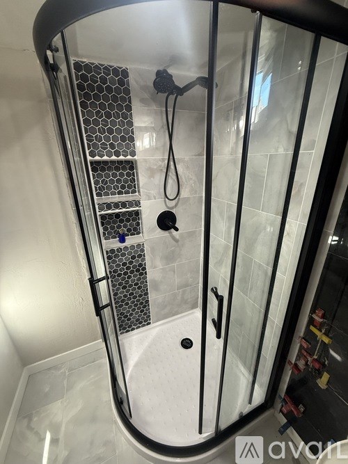 A shower with a glass door and a metal grate on the side.