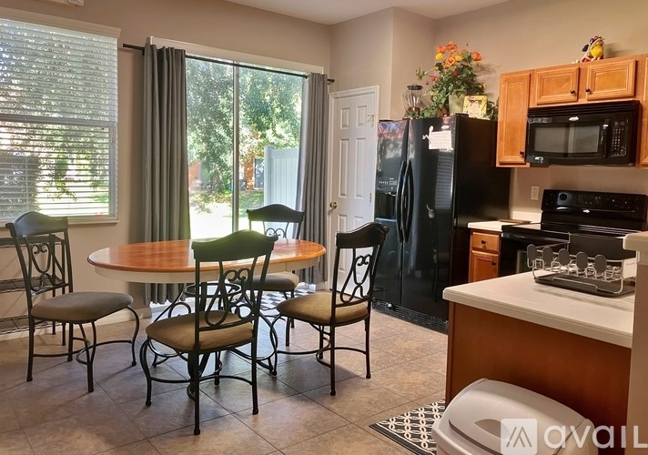 A kitchen with a table and chairs in front of a refrigerator.