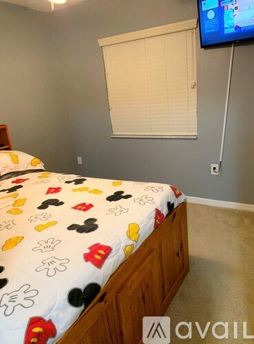 A bedroom with a bed, a TV, and a window with blinds.