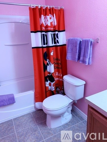 A bathroom with a toilet, a tub, a shower curtain and a towel.