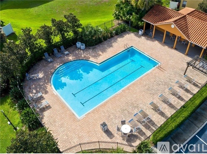 A pool surrounded by a brick patio and lawn chairs.