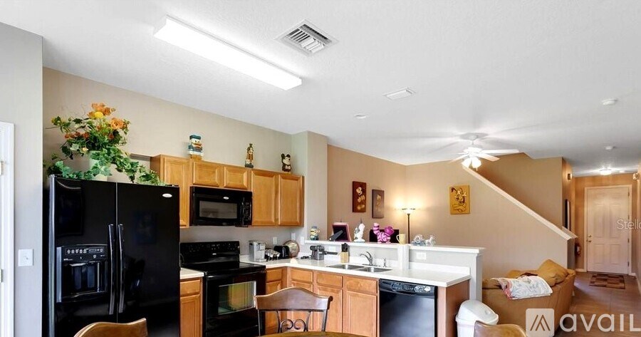 A kitchen with wooden cabinets and a black fridge.
