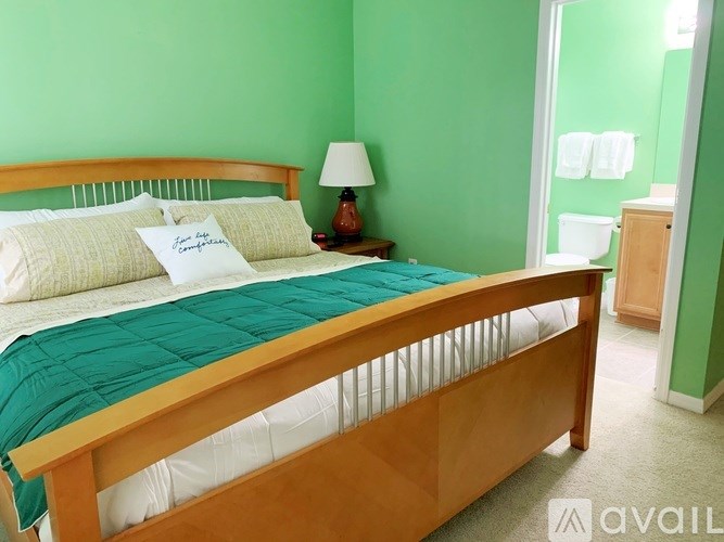 A bed with a green blanket and pillows in a room with green walls.